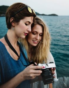 Two women ocean SLR camera