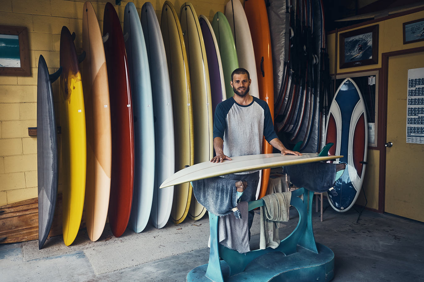 Man standing by row of surfboards