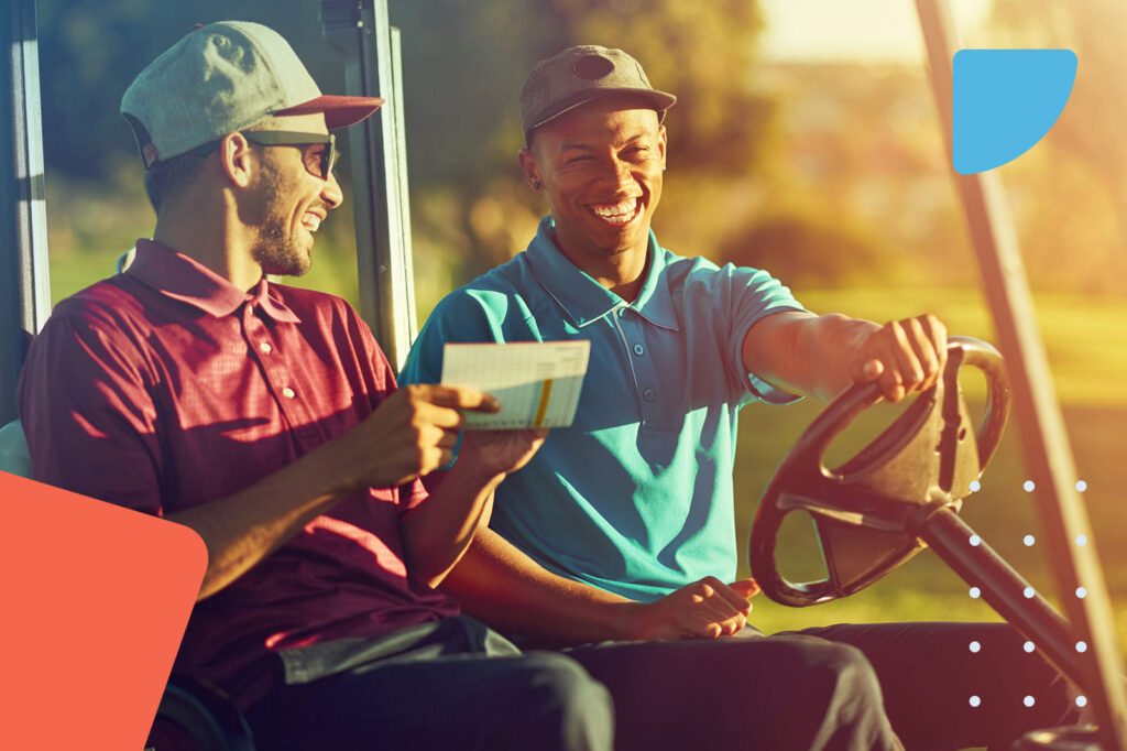 Two men laughing while driving a golf cart at sunset