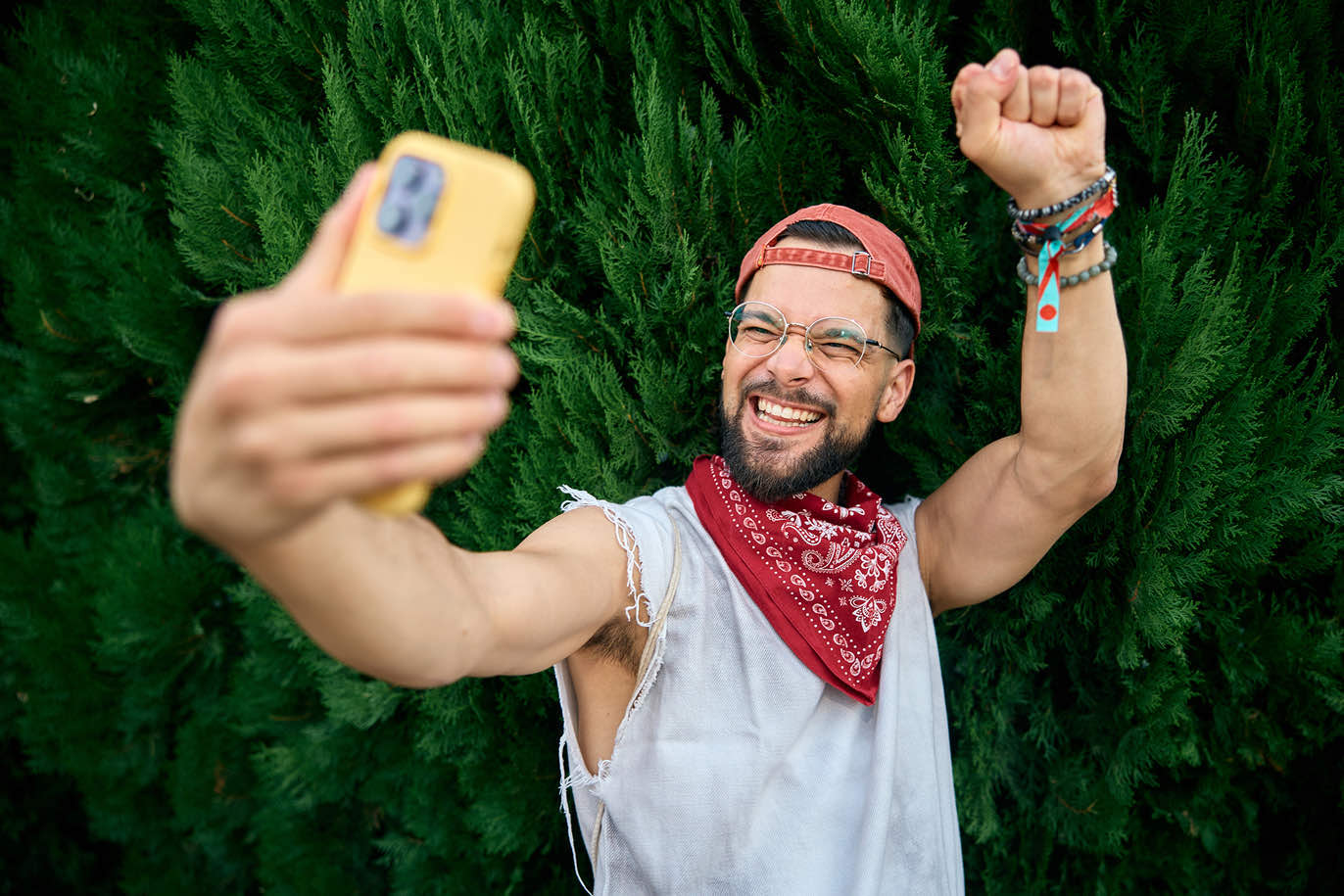 Man with bandana taking an enthusiastic outdoor selfie