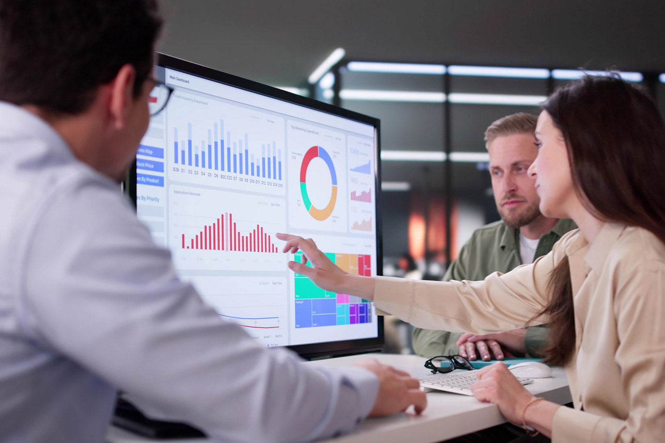 Analysts discussing data trends on a large computer monitor