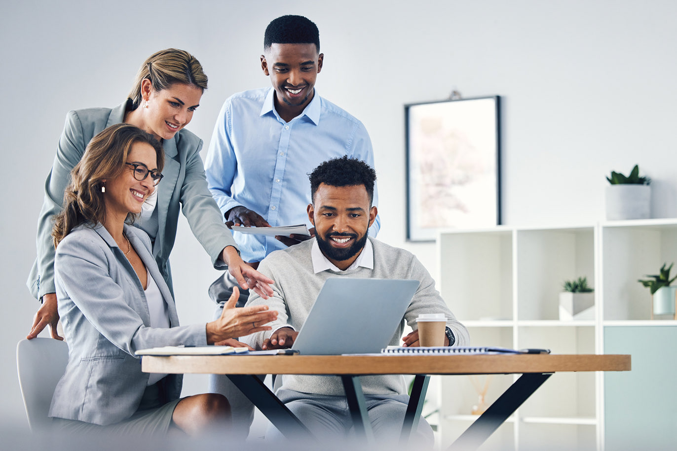 Team of young professionals collaborating around a laptop