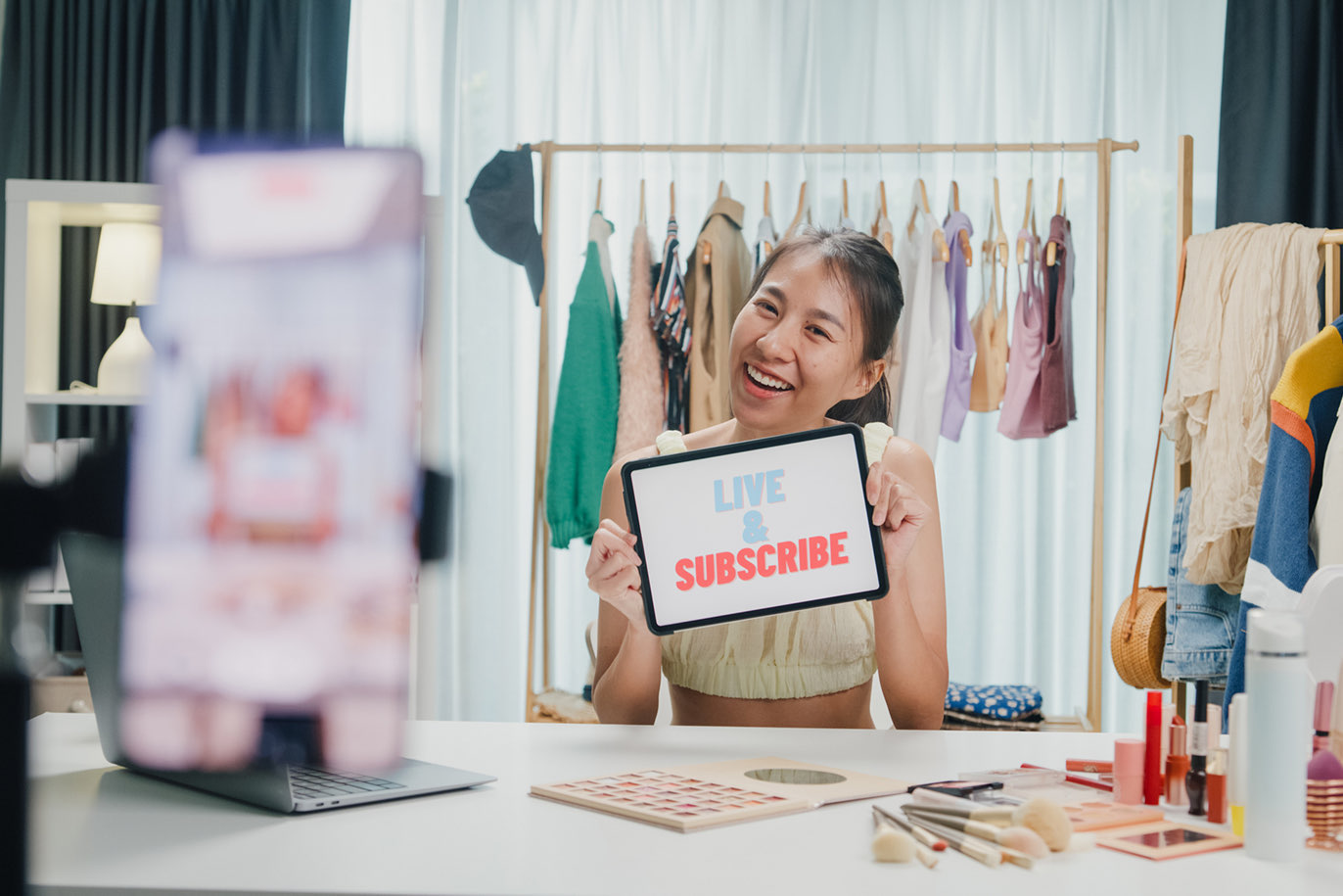 Livestreamer holding a "Live & Subscribe" sign