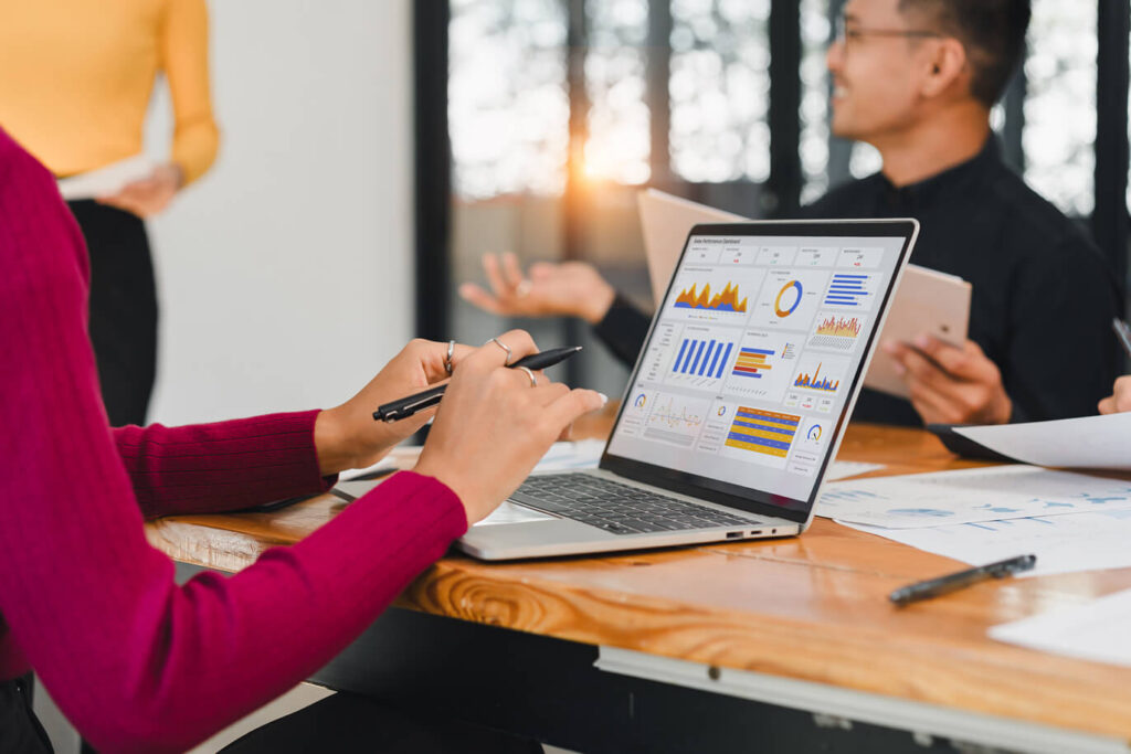 Team members are working together using brand ambassador management software on a laptop.