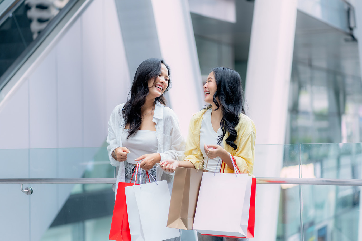 Two women laughing while carrying shopping bags