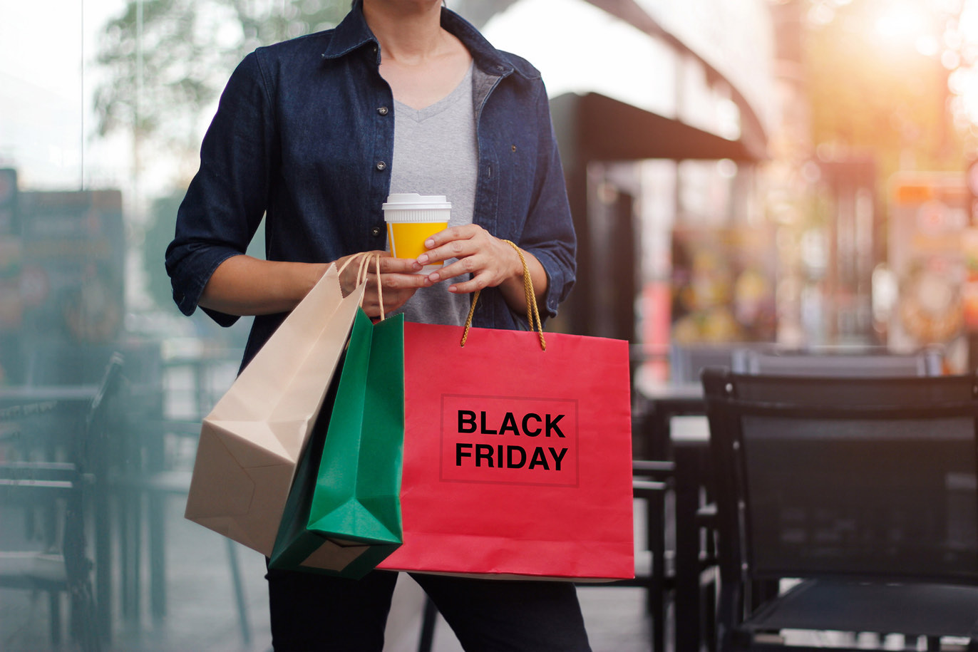 Person holding Black Friday shopping bags at a cafe