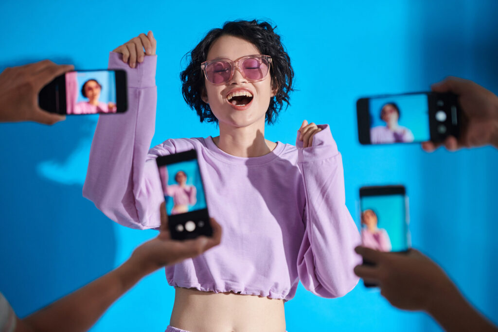 Influencer posing while being recorded by multiple smartphones
