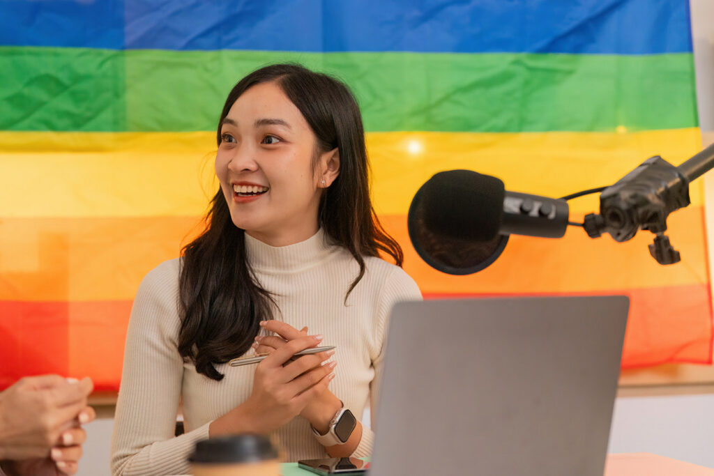 Woman recording podcast with pride flag