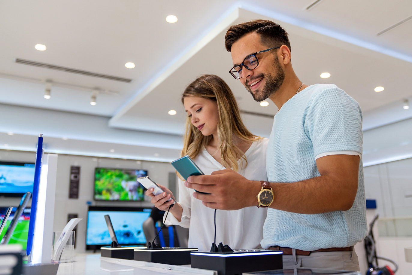 Couple comparing phones in a tech store