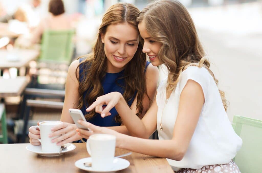 Two woman at coffee looking at mobile phone