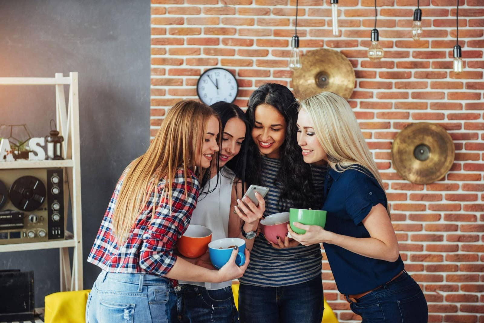 Four Woman looking at post on phone while drinking coffee