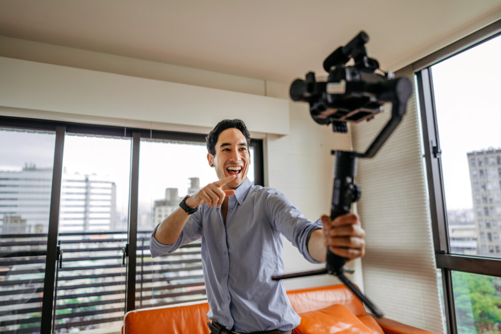 Joyful vlogger filming vlog on the move at apartment, holding professional camera. Recording content as part of an ambassador programs.