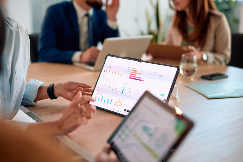 Tablet showing sales, pipeline, and revenue dashboards in a meeting, the kind of reporting an affiliate management system needs to organize 
