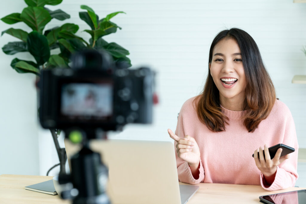 Ambassador recording branded video content with a camera, laptop, and smartphone for a brand ambassador platform.