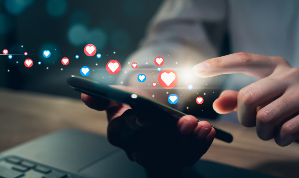 Person using a smartphone as social engagement icons appear, representing activity managed through a brand ambassador platform.